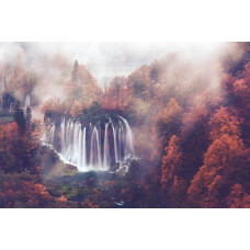 Fototapete mit einem Wasserfall, der durch einen nebligen Herbstwald fließt, umgeben von Bergen und Bäumen.