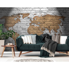 Eine Fototapete mit einer Weltkarte auf einer Steinwand in Gold-, Grau- und Gelbtönen.