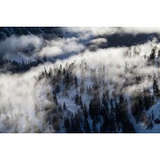 Fototapete einer Winterlandschaft mit schneebedeckten Bergen, wo ein dichter Nebel der Landschaft eine magische Atmosphäre verleiht.