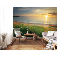 Eine Fototapete mit einem Meer bei Sonnenuntergang und einem Strand im Wohnraum.