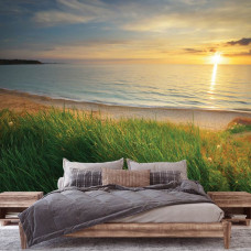 Eine Fototapete mit einem Meer bei Sonnenuntergang und einem Strand im Schlafzimmer.
