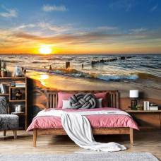 Ein Fototapete mit einem natürlichen Sonnenuntergang über einer Strandlandschaft, passend für ein Schlafzimmer.