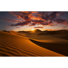 Fototapete mit einem Sonnenuntergang in der Wüste, bei dem die Berge von den letzten Strahlen der Sonne beleuchtet werden.