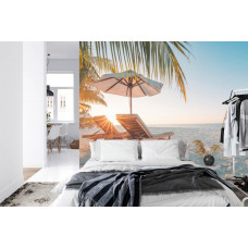 Eine sommerliche Fototapete mit Strandliegen unter einem tropischen Sonnenuntergang, perfekt für ein Schlafzimmer.