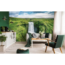 Eine Fototapete mit einem großen Wasserfall in einer Berglandschaft, die im Wohnzimmer zu sehen ist.