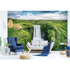 Eine Fototapete mit einem großen Wasserfall in einer Berglandschaft, die im Wohnzimmer zu sehen ist.