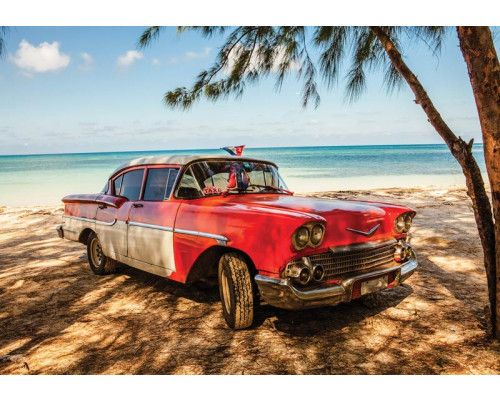 Fototapete mit einem klassischen kubanischen Auto, das an einem Strand mit Palmen und azurblauem Meer entlangfährt, ideal für einen Vintage-Look.