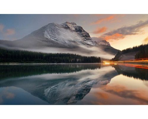 Fototapete eines bezaubernden Bergsees, umgeben von Bergen und Wäldern, die eine heitere und friedliche Atmosphäre ausstrahlen.