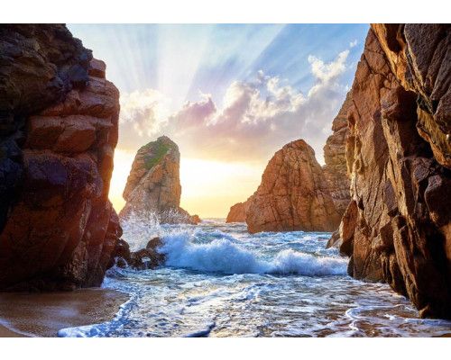 Fototapete von Wellen, die zwischen Felsen brechen, mit den Bergen im Hintergrund in einer üppigen Naturlandschaft.