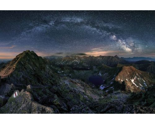 Die Milchstraße leuchtet über Bergen und Sternen, wunderschön dargestellt auf dieser natürlich wirkenden Fototapete.
