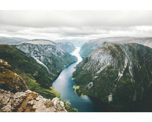 Fototapete vom Naeroyfjord in Norwegen, wo Berge und Fluss in einer unberührten Naturlandschaft aufeinandertreffen.