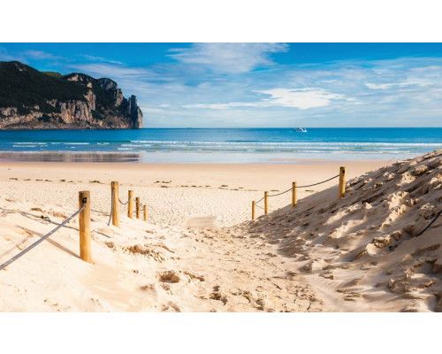 Fototapete mit Strand und Meerblick, klares blaues Meer mit einer warmen Sonne am Horizont.