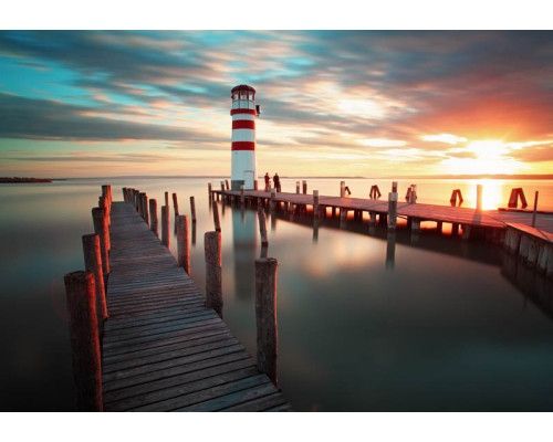 Fototapete eines Sonnenuntergangs an einem Leuchtturm an der Küste, mit atemberaubendem Blick auf das Meer und die Natur.