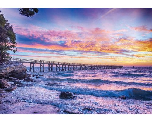 Sonnenuntergang über dem Meer mit einem Pier in der Ferne, eingefangen auf Fototapete.