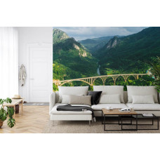 Eine Fototapete mit der Durdevica Tara-Brücke in Montenegro und den umliegenden Bergen, abgebildet in einem Wohnzimmer.