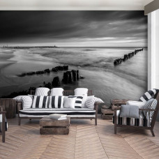 Eine Fototapete mit einer schwarz-weißen Strandlandschaft bei Sonnenuntergang im Wohnzimmer.