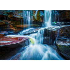 Fototapete mit mehreren Wasserfällen zwischen dunklen Felsen und blauem Wasser.