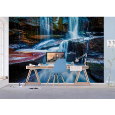 Büro mit Fototapete Wasserfall zwischen Felsen, Schreibtisch und blauem Bürostuhl.