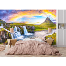 Fototapete Wasserfälle und Kirkjufell bei Sonnenuntergang in Island mit breitem Wasserfall, grünen Felsen und bunten Wolken im Schlafzimmer.