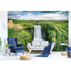 Eine Fototapete mit einem großen Wasserfall in einer Berglandschaft, die im Wohnzimmer zu sehen ist.