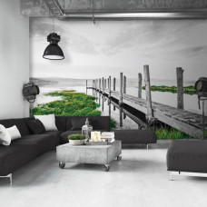 Eine Fototapete von einem Steg am See in einer Landschaft, die im Wohnzimmer zu sehen ist.