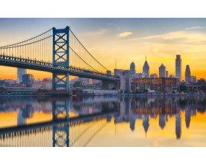 Ben-Franklin-Brücke in Philadelphia mit einer Spiegelung im Wasser bei Sonnenuntergang, abgebildet auf einer Fototapete.