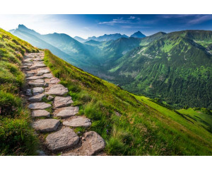 Fototapete eines Bergpfads, der sich entlang der Berggipfel schlängelt, mit weitem Blick über die Landschaft.