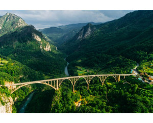 Die Durdevica-Tara-Brücke in Montenegro, umgeben von den Tara-Bergen und abgebildet auf einer Fototapete mit einer Berglandschaft.