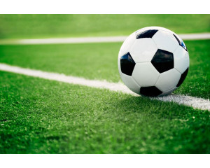 Fototapete eines Fußballs auf einer Wiese liegend, bereit für den Einsatz während eines spannenden Moments im Spiel.