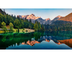 Reflektierender Bergsee mit Wäldern und Bergen, die sich im klaren Wasser spiegeln, abgebildet auf einer natürlich wirkenden Fototapete.