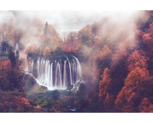 Fototapete eines Wasserfalls, der durch einen nebligen Herbstwald fließt, umgeben von Bergen und Bäumen.