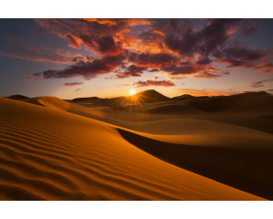 Fototapete eines Wüstensonnenuntergangs, bei dem die Berge von den letzten Sonnenstrahlen beleuchtet werden.